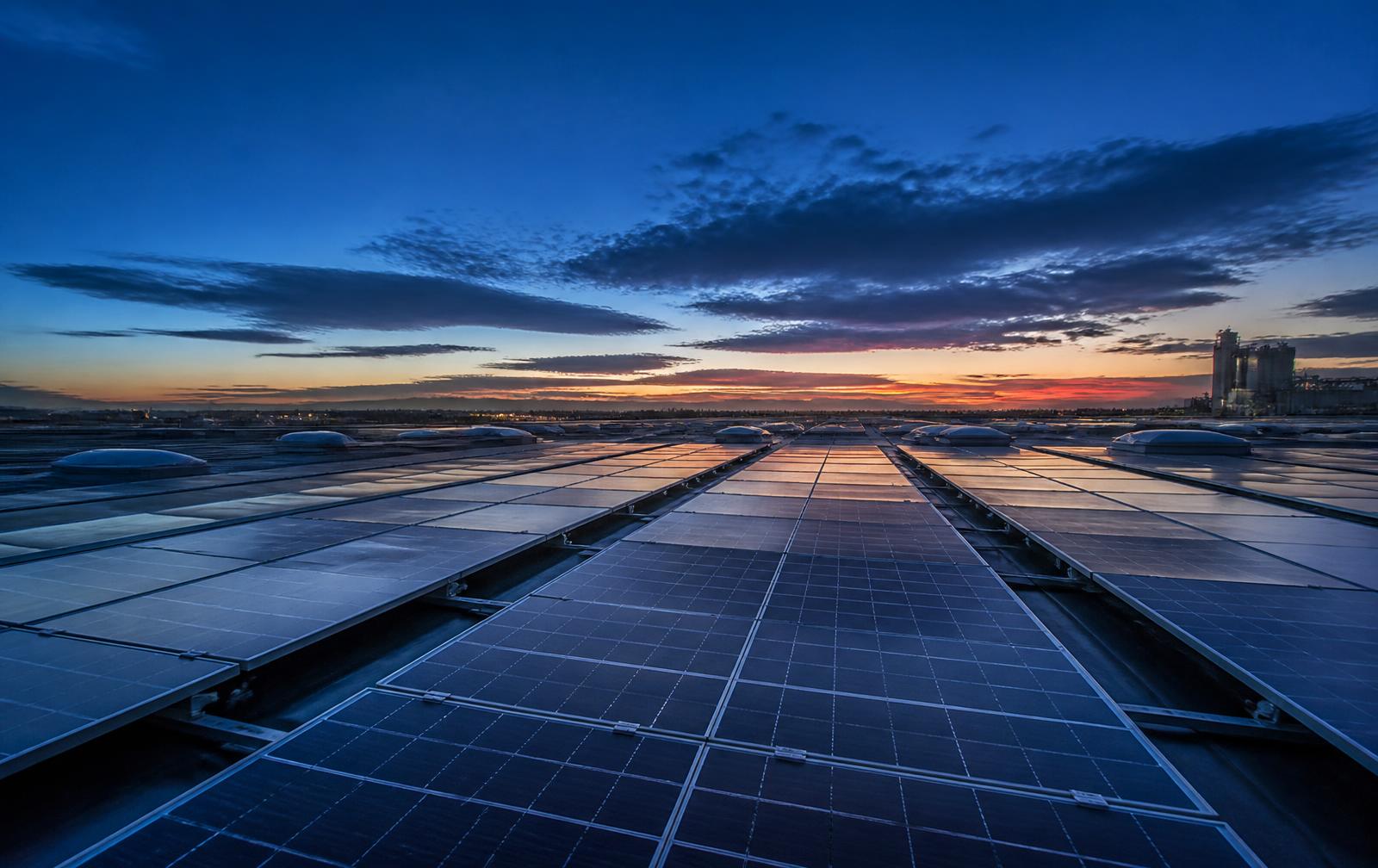 Illustrative image: rows of industrial solar panels at dusk.